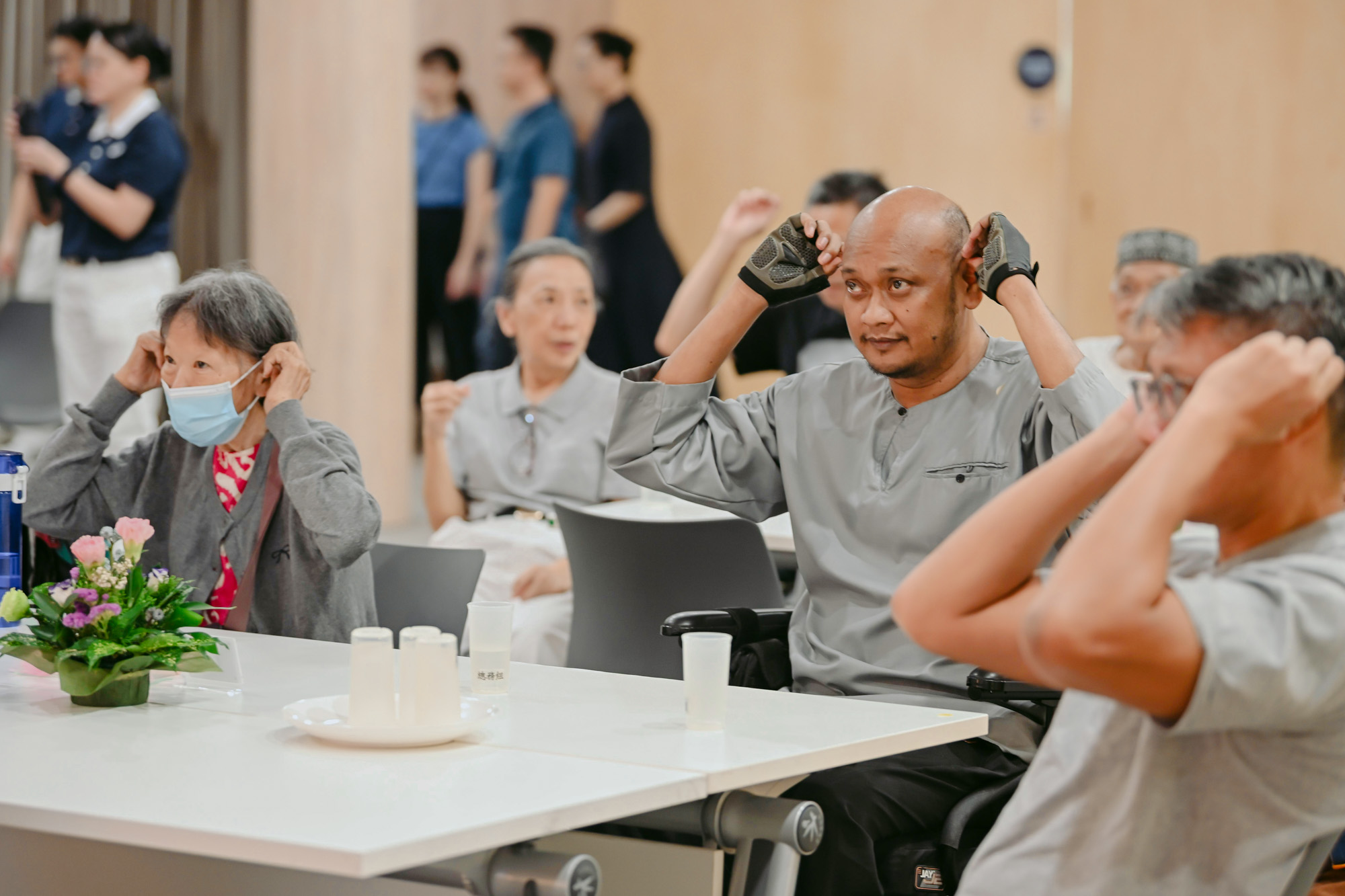与会者认真学习着医生教的耳穴按摩步骤。摄/ 蔡佑良